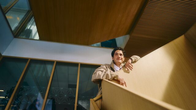 Young adult man standing with confidence on a wooden office staircase small